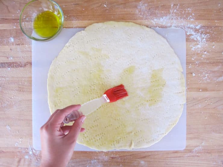 Brushing olive oil on a pizza crust.