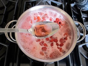 Skimming foam from simmering raspberries.