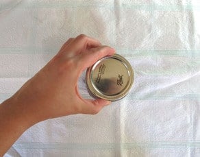 Adding canning lids to jars finger tight.