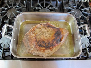 Browned beef brisket in a roasting pan.