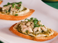 Three Tuna, hummus, and pesto crostini appetizer served on a white plate