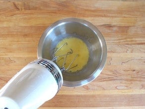 Beating eggs and milk with a hand mixer.