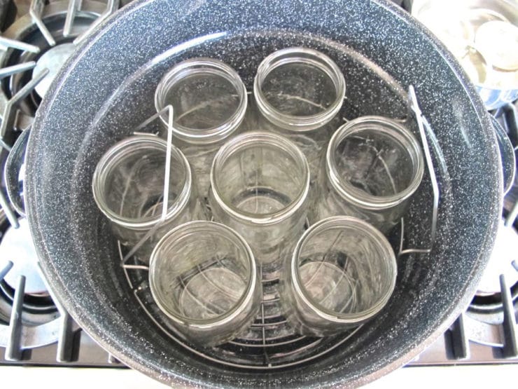 Round rack at the bottom of canning pot filled with jars on top of rack.