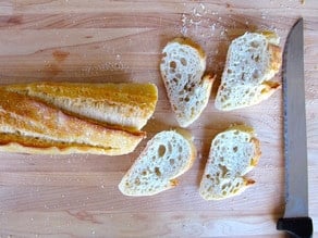 Thinly sliced baguette on a cutting board.
