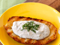 A slice of bread topped with a dip made of eggplant, tahini, and basil