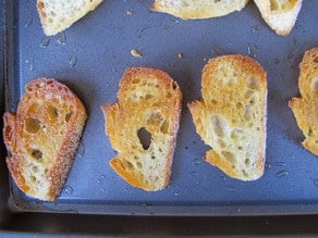 Toasted crostini on a baking sheet.