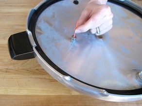 Hand cleaning out pressure canner lid vent pipe with toothpick.