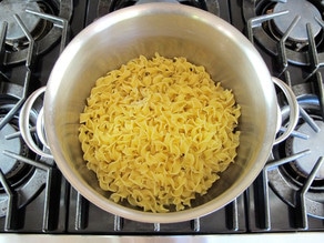 Egg noodles cooking in a large pot.