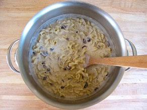 Egg mixture stirred into noodles in a large pot.