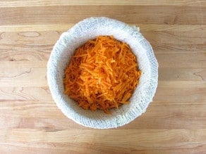Shredded carrots in cheesecloth for straining.