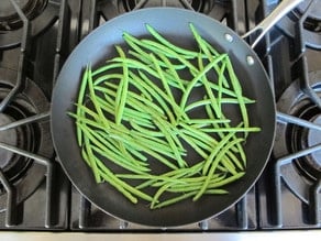 Saute green beans in a saucepan.
