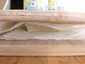 Block of tofu between cutting boards to press.