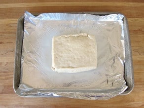 Pressed tofu on a foil lined baking sheet.