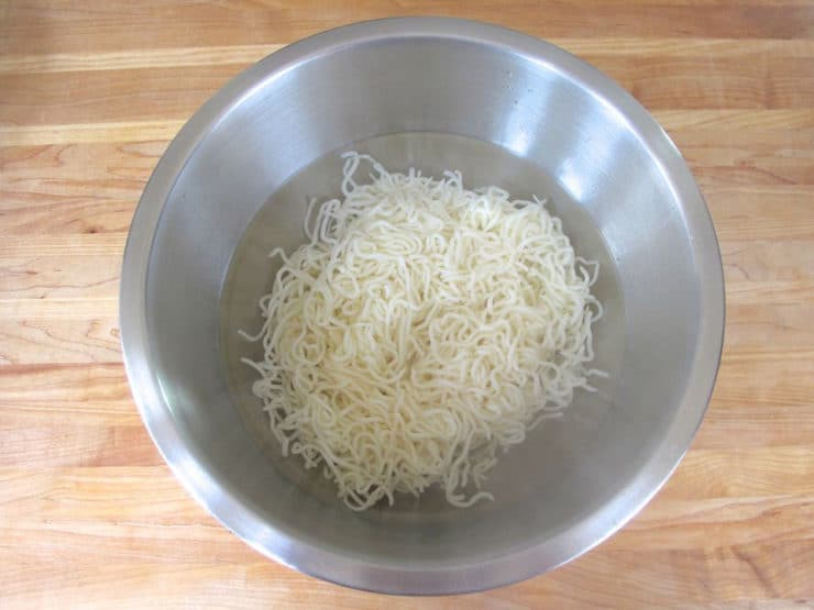 Rice noodles in a bowl of boiling water.