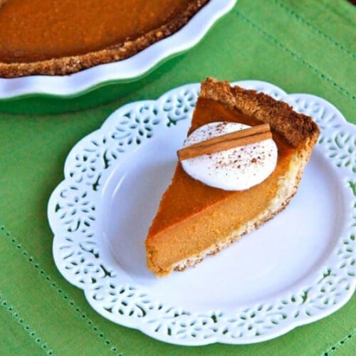 A delicious macaroon pumpkin pie with a golden crust, topped with coconut cream and a sprinkle of cinnamon