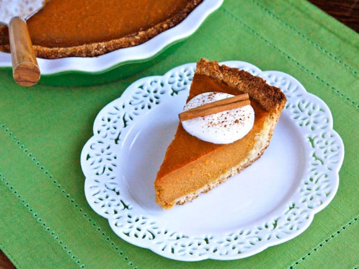 A delicious macaroon pumpkin pie with a golden crust, topped with coconut cream and a sprinkle of cinnamon