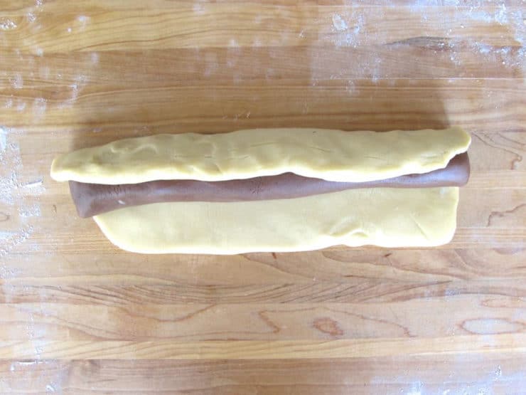 Wrap white dough rectangle around dark dough log.