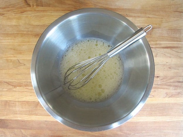 Eggs in a mixing bowl beaten with water and salt.