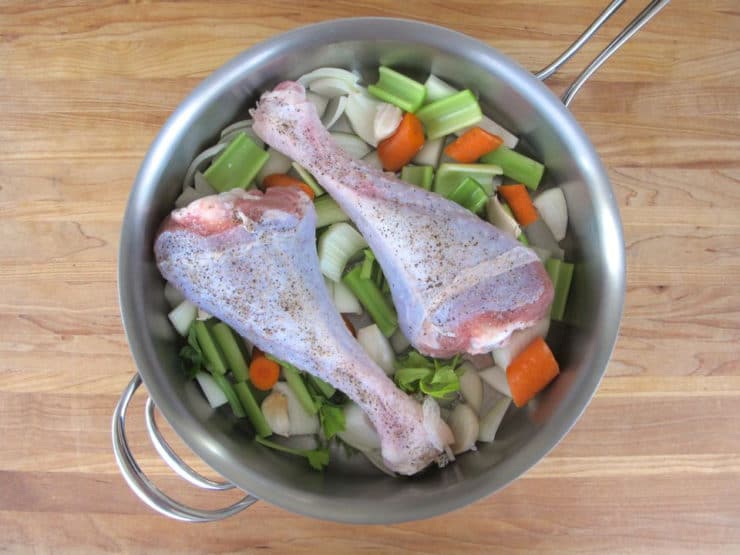 Turkey legs and vegetables in a saucepan.