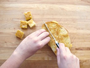 Cubing grilled cheese sandwiches for croutons.