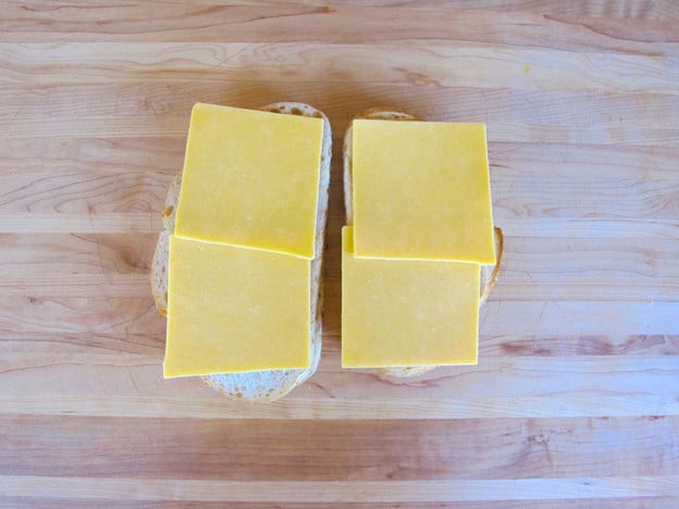 Place sliced cheese on buttered bread.