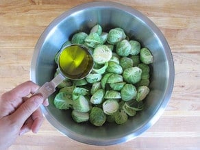 Tossing brussels sprouts with oil in a mixing bowl.