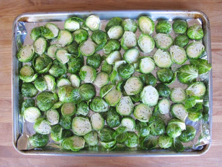 Brussels sprouts spread on a foil-lined baking sheet.
