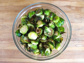 Tossing roasted brussels sprouts with toasted walnuts.