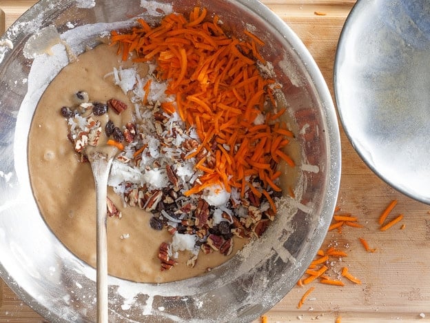 Shredded carrots and other additions being stirred into batter.