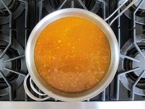 Simmer stock and vegetables until sauce is bright orange.