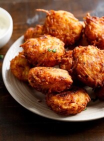 Latkes on a white plate with sour cream.