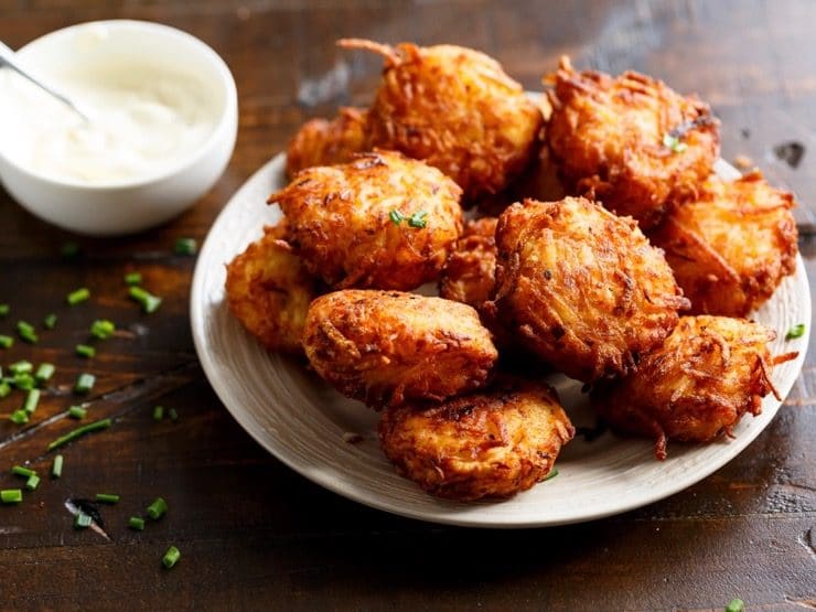 Latkes on a white plate with sour cream.