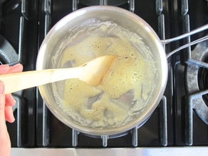 Adding flour to melted butter for a roux.