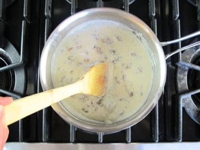 Stirring raisins and seasoning into white sauce.