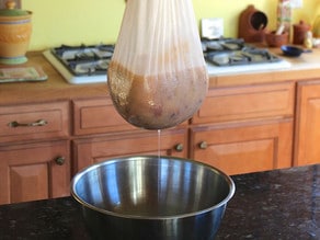 Straining apple juice from the pulp using cheesecloth.
