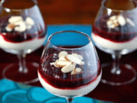 Three glasses of Cherry Cheesecake Shooters topped with almonds and berries, a delightful dessert