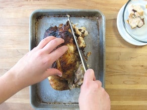 Cutting the meat off a rotisserie chicken.