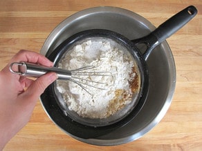 Sifting all dry ingredients into a mixing bowl.