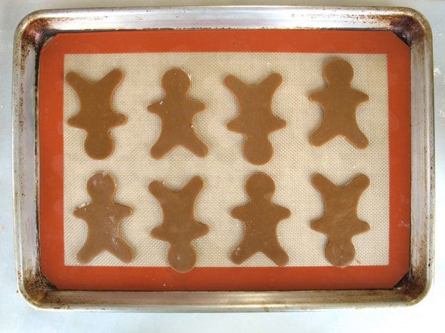 Gingerbread men on a silicone lined baking sheet.