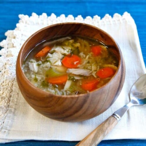 Horizontal shot of Rotisserie Chicken Rice Soup on a brown bowl and a spoon on top of a white cloth.