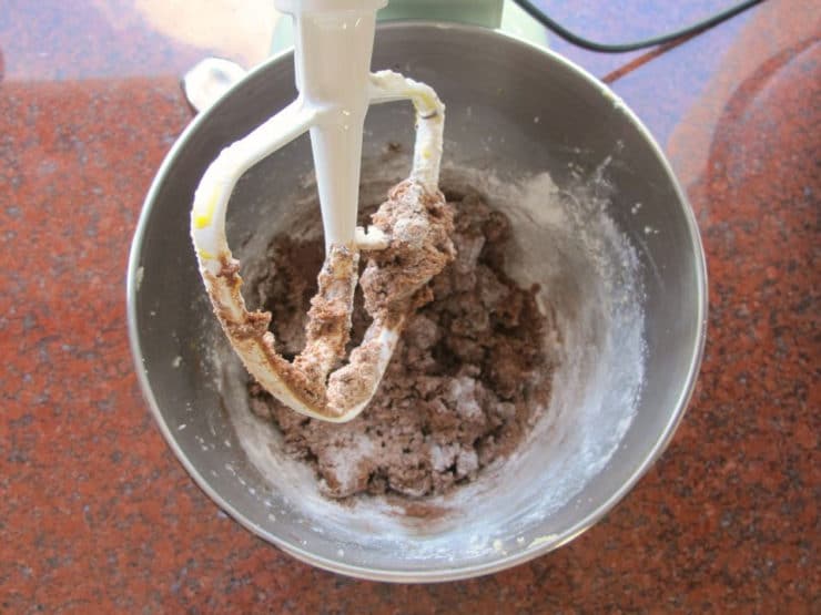 Adding flour into chocolate butter in mixer.