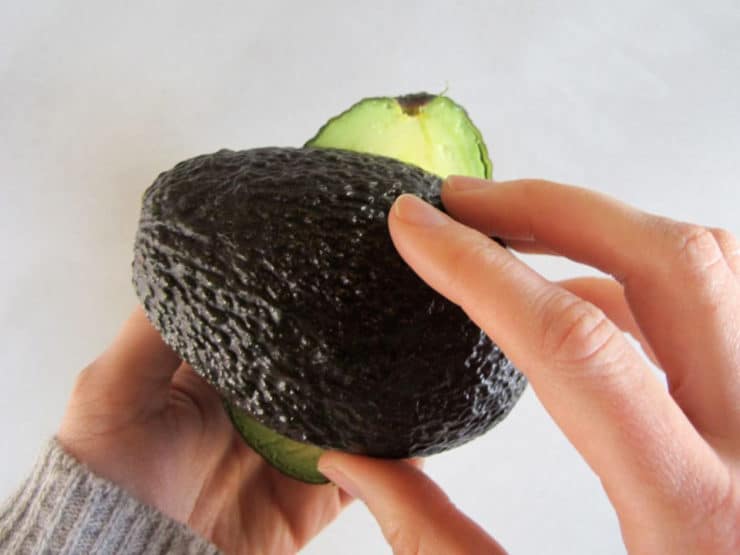Twisting avocado halves apart.