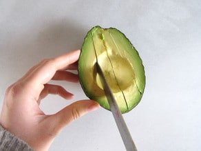 Slicing avocado still in the peel.