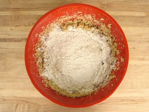 Mixing flour into wet ingredients in a mixing bowl.