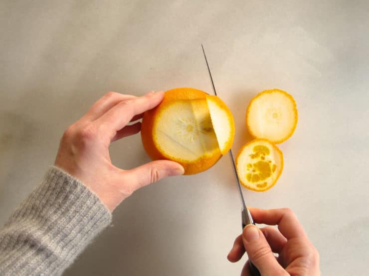 Cutting a slice of peel off an orange.