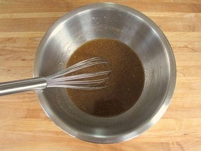 Orange juice and spices whisked together in a mixing bowl.