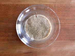 Water added to ground chia seeds in a small bowl.