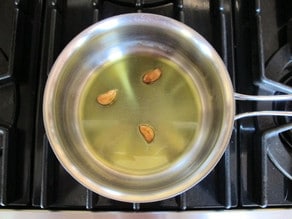 Roasting garlic cloves in oil.