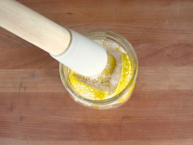 Tightly packing a jar with lemons.