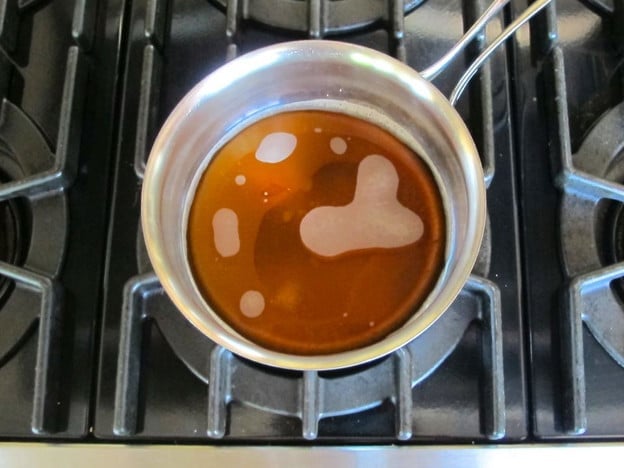 Heating maple syrup and sugar in a saucepan.